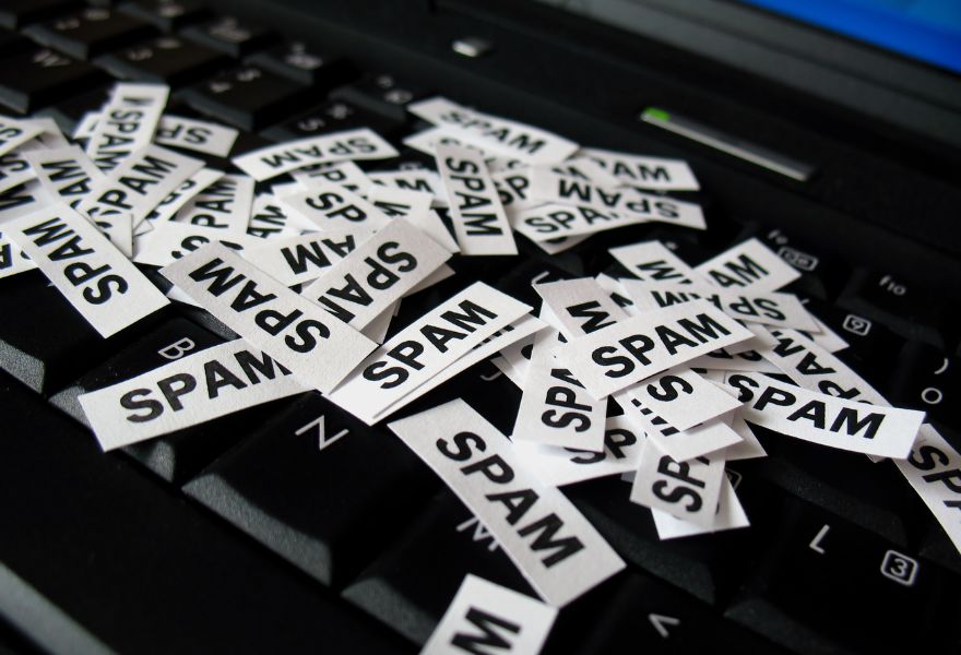 Tiny snips of paper with word Spam on them sitting on black keyboard